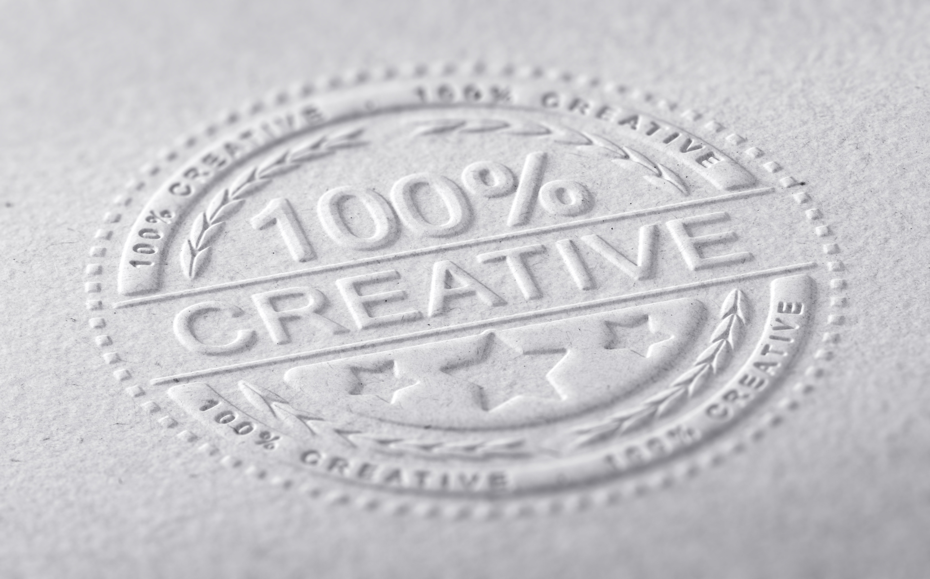 3D illustration of a stamp embossed on a paper texture with the text one hundred percent creative, horizontal image. Communication concept for creative advertising company